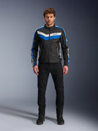 Veste Alpinestars T-Dyno WR, veste de moto en textile, noir, bleu et écru, portée par un mannequin homme avec un pantalon et des bottes noirs, arborant des bandes en chevron sur la poitrine et un design biker héritage