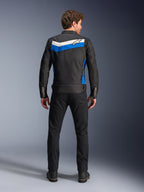 Veste Alpinestars T-Dyno WR, veste de moto en textile, coloris noir, bleu et écru, vue de dos complète sur mannequin, présentant une bande en chevron bleue et blanc cassé avec le logo Alpinestars, associée à un pantalon et des bottes noirs, équipement de conduite urbaine d'inspiration vintage