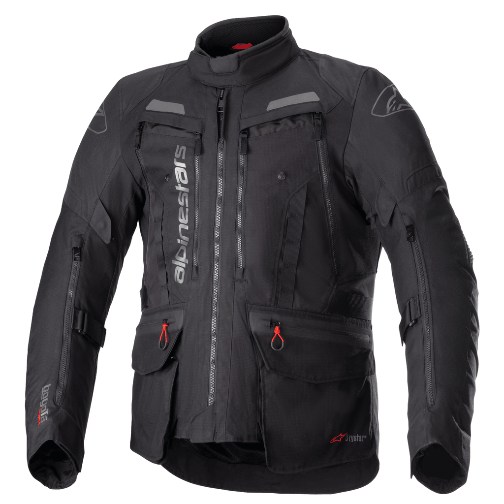 Veste Alpinestars Bogota Pro Drystar, veste de moto touring noire, accents gris et rouges, dotée de larges panneaux de ventilation sur la poitrine, poches imperméables avec tirettes rouges, col protecteur haut et construction textile durable pour le pilotage d'aventure