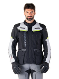 Man wearing Alpinestars Bogotá Pro Drystar® Jacket, Black Ice Gray and Yellow Fluo, all-season adventure touring motorcycle jacket, waterproof design with multiple pockets and vertical branding, paired with black gloves and gray riding pants