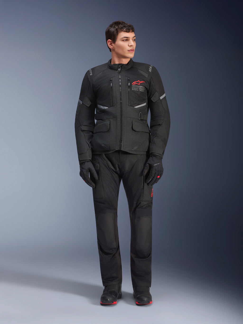 Alpinestars Andes Air Drystar® broek, motor touringbroek, zwart, voorzien van mesh ventilatiepanelen en een rood logo op de broekspijp, gedragen als onderdeel van een complete motoroutfit met bijpassende jas en handschoenen, professionele adventure touring uitrusting