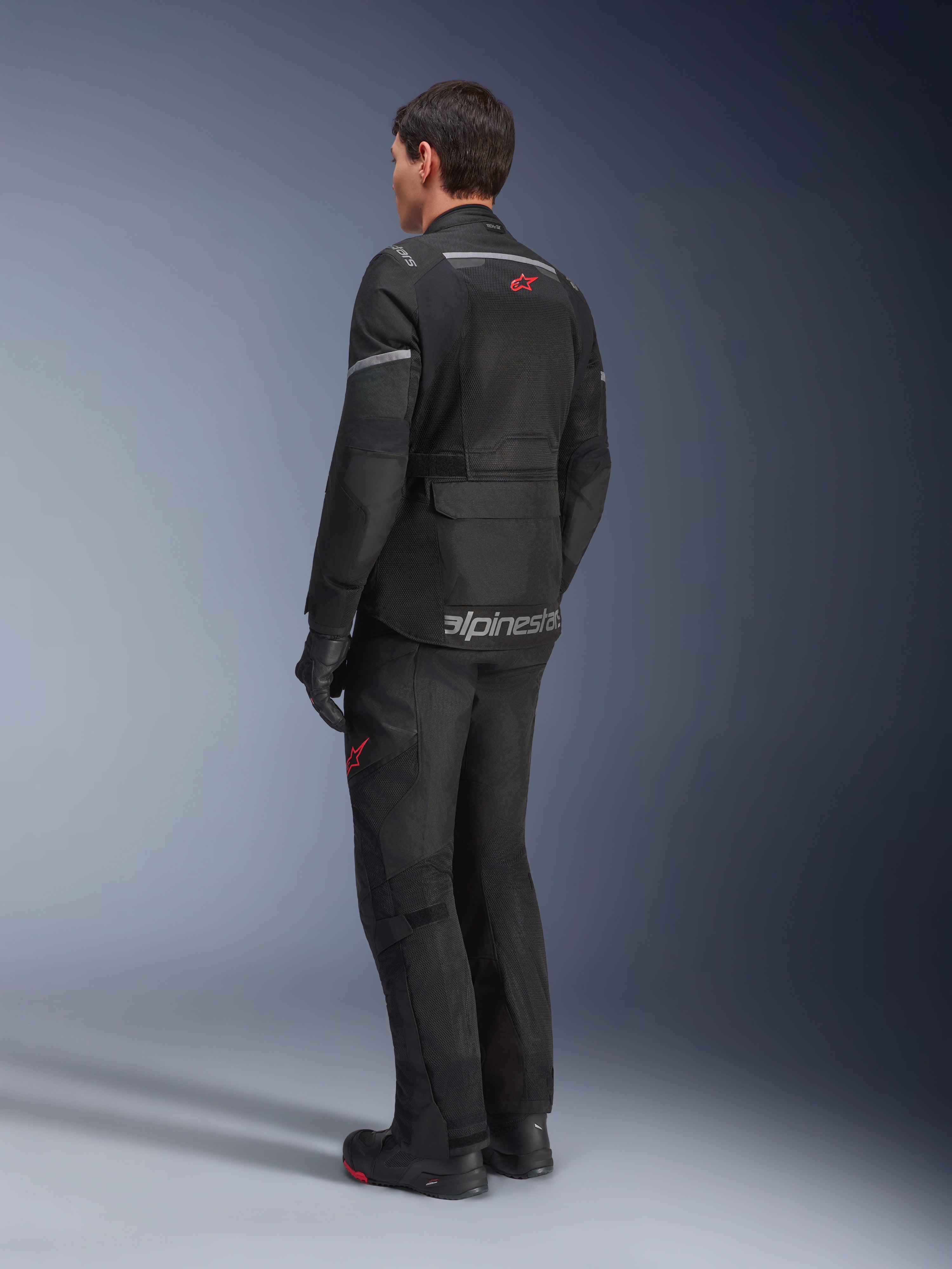 Alpinestars Andes Air Drystar® broek en bijpassende jas, zwart met rode sterlogo's, adventure touring motorkleding van achteren gezien, met mesh-ventilatiepanelen en reflecterende details