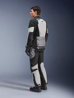 Fahrer trägt Alpinestars Andes Air Drystar® Jacke und Hose, Adventure-Tourenbekleidung in Ice Gray Dark Gray Black mit neongelben Akzenten, mit großflächigen Mesh-Einsätzen für Luftzirkulation, Alpinestars-Logo auf dem Rücken, kombiniert mit schwarzen Handschuhen und Stiefeln.