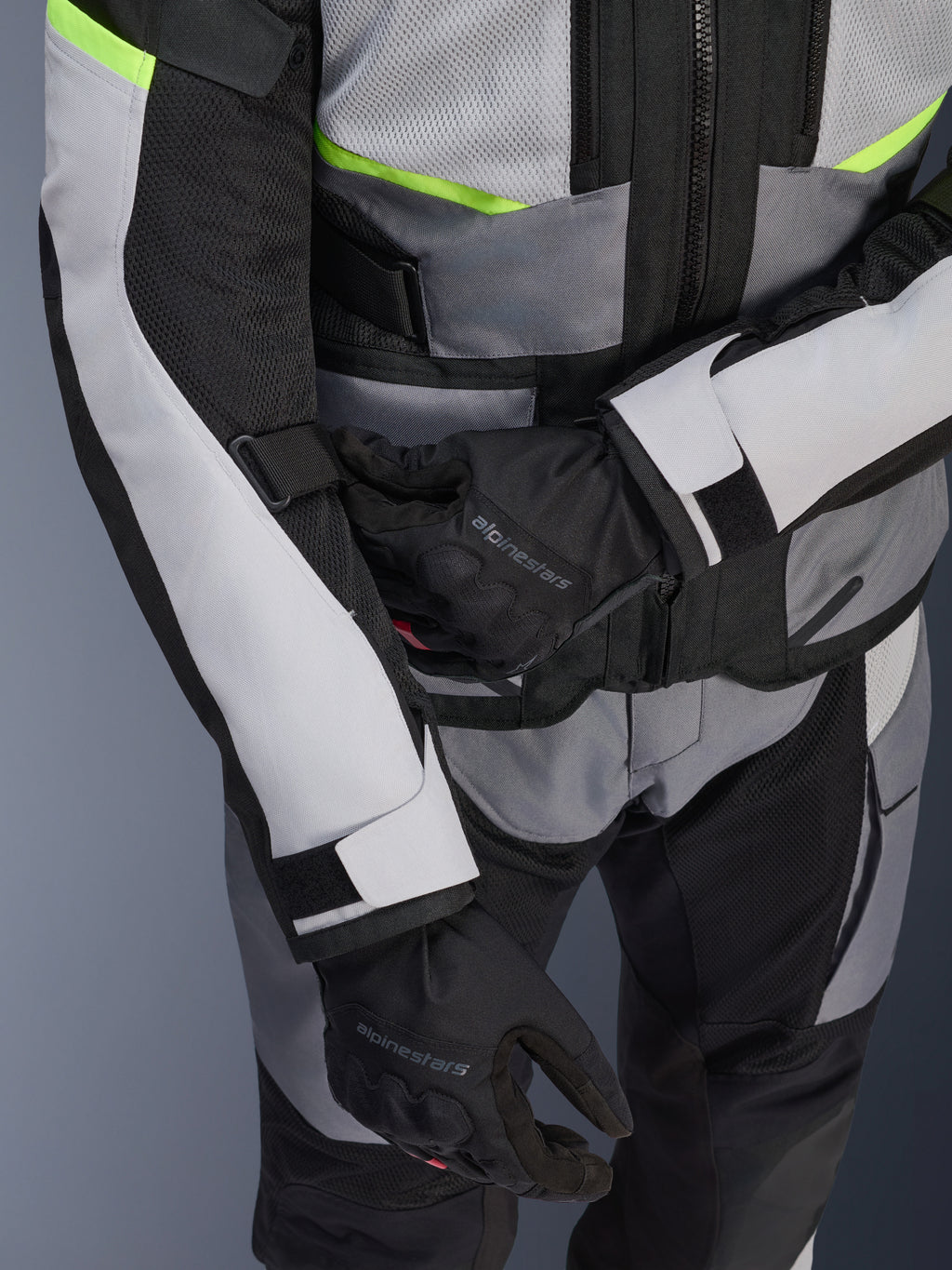 Alpinestars Andes Air Drystar® Jacke, Motorrad-Tourenjacke, Ice Gray und Dark Gray mit neongelben Akzenten, Nahaufnahme mit Mesh-Einsätzen und Verstellriemen, getragen mit schwarzen Alpinestars Handschuhen
