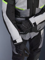Alpinestars Andes Air Drystar® Jacke, Motorrad-Tourenjacke, Ice Gray und Dark Gray mit neongelben Akzenten, Nahaufnahme mit Mesh-Einsätzen und Verstellriemen, getragen mit schwarzen Alpinestars Handschuhen