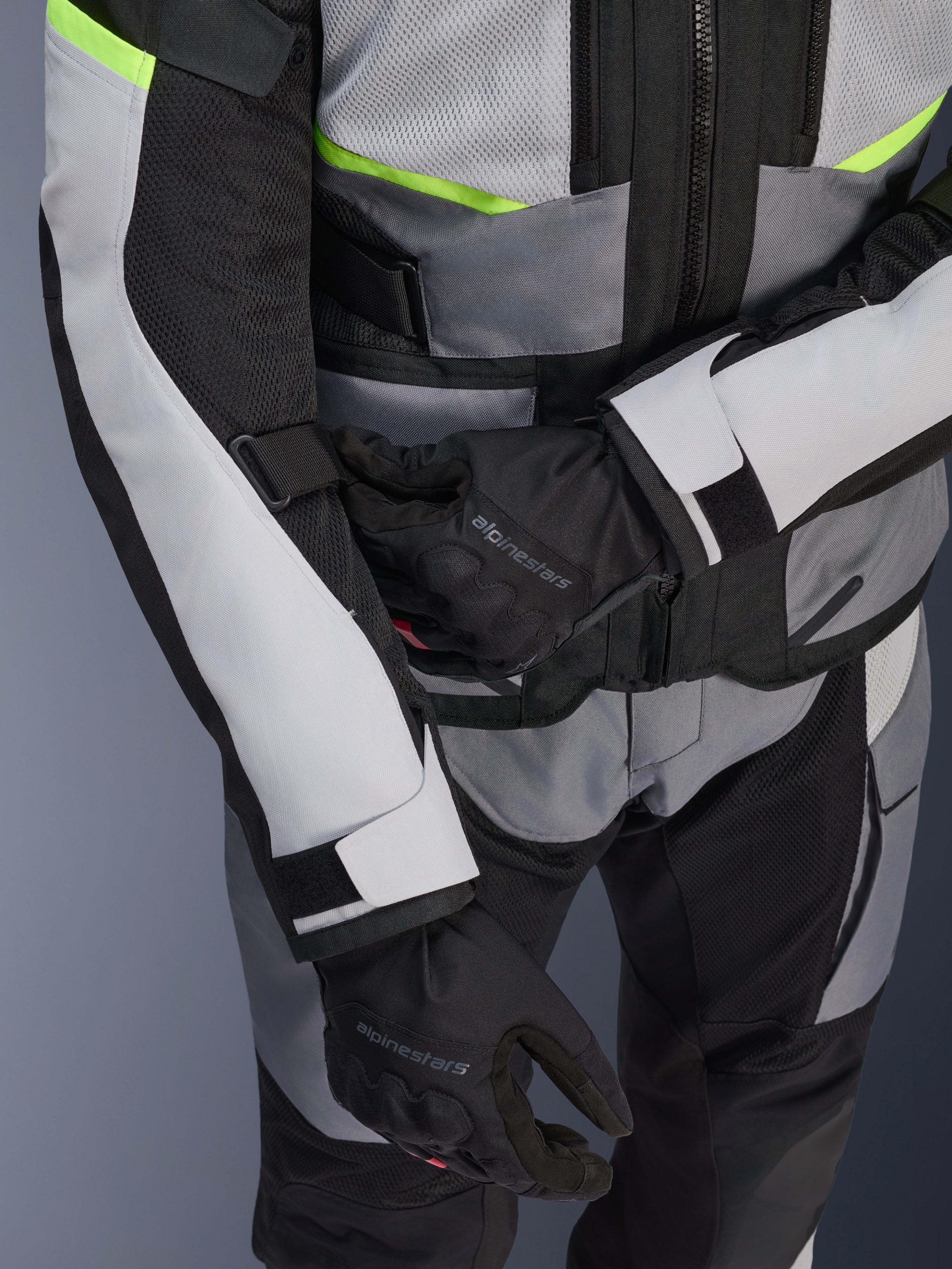Alpinestars Andes Air Drystar® Jacke, Motorrad-Tourenjacke, Ice Gray und Dark Gray mit neongelben Akzenten, Nahaufnahme mit Mesh-Einsätzen und Verstellriemen, getragen mit schwarzen Alpinestars Handschuhen