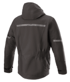 Alpinestars Sirius Drystar® Techshell Jacket, motorjas, Melange Black, achteraanzicht met geïntegreerde capuchon, reflecterende strip met Alpinestars-logo, elastische taille en verlengde achterkant voor extra dekking tijdens het rijden.