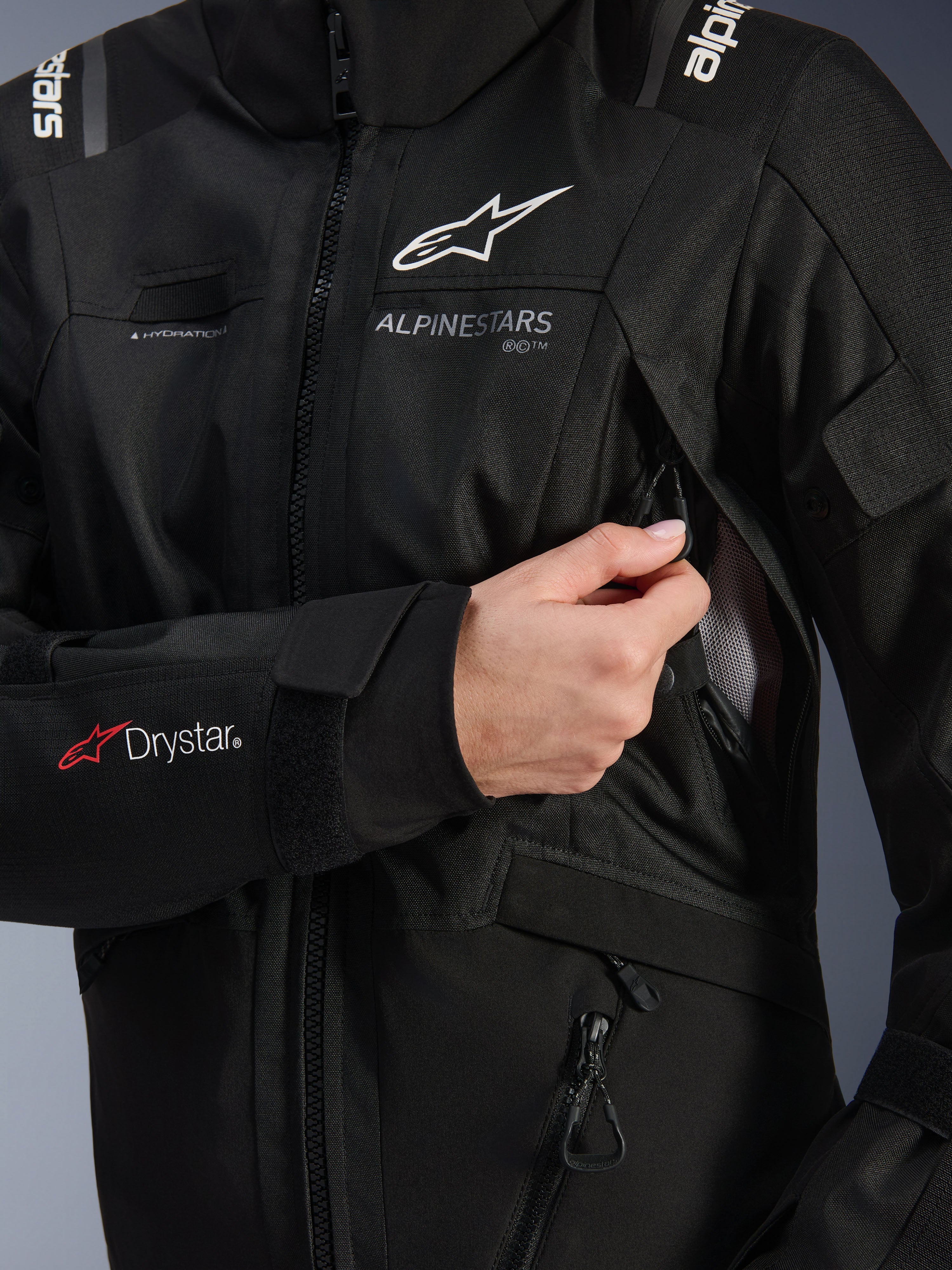 Alpinestars Woman Stella Andes V4 Drystar® Jacket, Black, detail shot showing the chest ventilation intake being opened, featuring mesh lining, Drystar® logo on the forearm, and hydration hose loop, technical motorcycle apparel