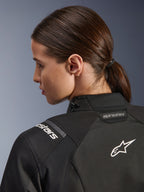 Alpinestars Woman Stella Andes V4 Drystar® Jacket, Black, close-up view of the upper back and shoulder, featuring white embroidered Astar logo and branding, technical textile construction for motorcycle adventure riding