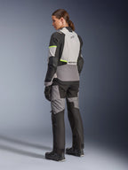 Veste femme Alpinestars Stella Andes V4 Drystar®, veste de moto touring aventure, gris glace et gris foncé avec des accents jaune fluo, vue arrière sur un mannequin portant un pantalon textile assorti, dotée d'une construction imperméable et de panneaux ripstop renforcés.
