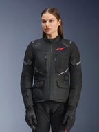 Alpinestars Stella Andes Air Drystar Jacket, veste de moto touring pour femme, noire avec des accents gris et un petit logo rouge, dotée de panneaux de ventilation en mesh, d'un col haut et de multiples poches utilitaires, portée avec des gants et un pantalon de moto assortis