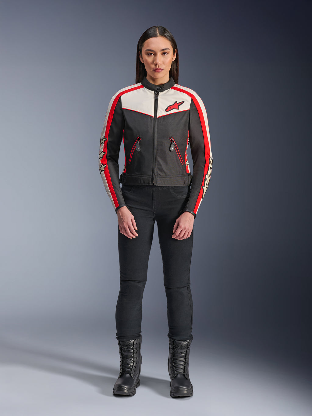 Alpinestars Stella T-Dyno WR Jas, textiele motorjas voor dames, zwart, ecru en felrood, gedragen door model met zwarte broek en laarzen, vintage-geïnspireerd ontwerp met rood Alpinestars logo en contrastpanelen.