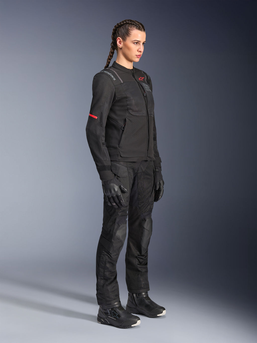 Mannequin portant la veste Alpinestars Stella ST-2 Air noire, accompagnée d'un pantalon, de gants et de bottes de moto noirs assortis, avec panneaux de ventilation en mesh et détails rouges discrets, tenue de touring moderne et épurée