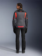 Rückansicht eines Models in der Alpinestars Stella ST-2 Air Damenjacke in Deep Gray und Dark Gray mit Fluo Coral Akzenten, mit großen Mesh-Belüftungseinsätzen am Rücken und reflektierenden Logo-Details, kombiniert mit einer schwarzen Motorradhose und Handschuhen.
