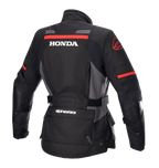 Veste Alpinestars Stella Honda Andes V3 Drystar® pour femme, veste de moto aventure, noir, gris goudron et rouge vif, vue arrière avec logo HONDA blanc et graphismes Alpinestars rouges, construction textile imperméable avec taille ajustable et poches utilitaires