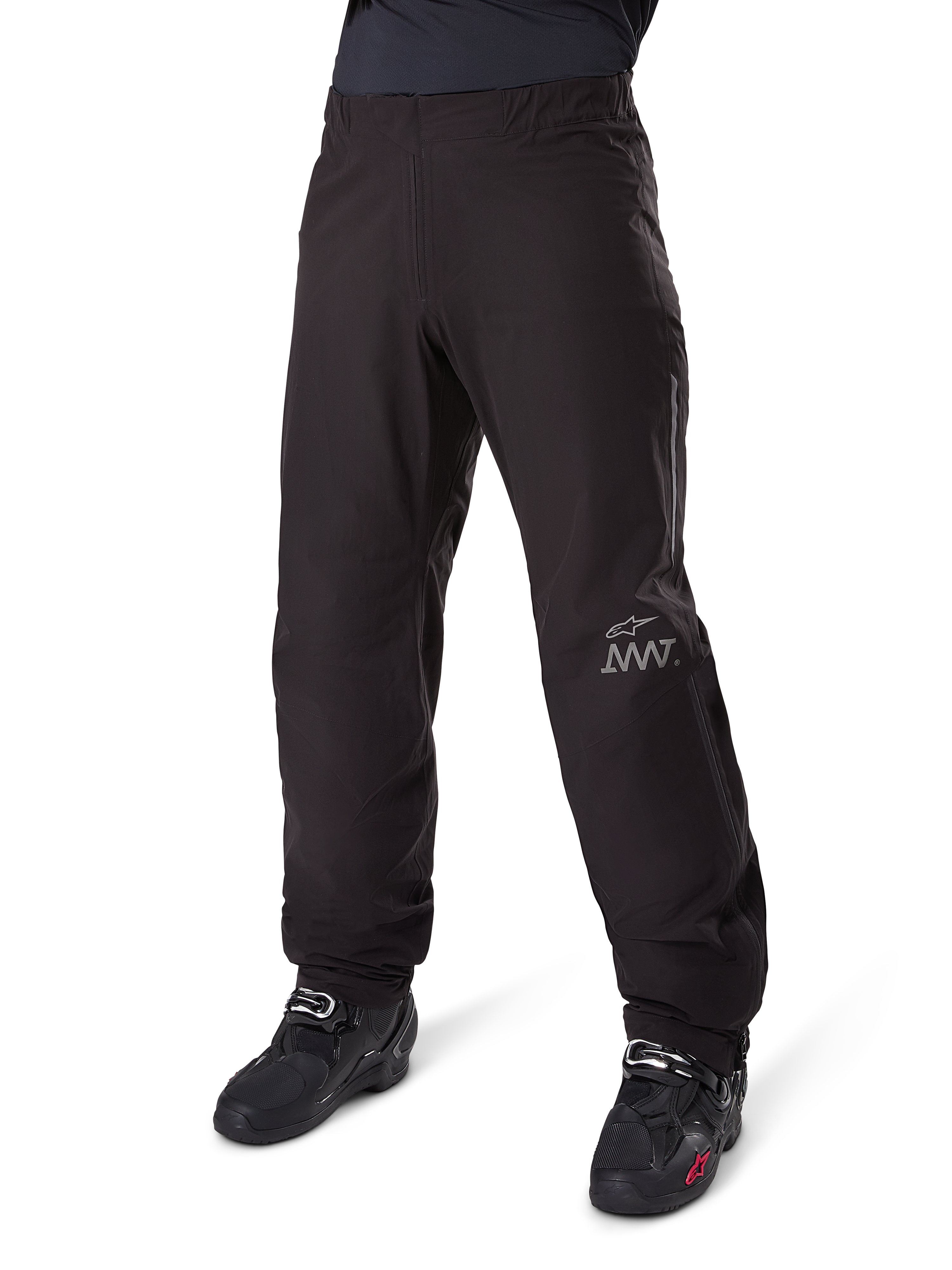 Doublure de pantalon Alpinestars Amt 8 Stretch Drystar® XF, pantalon de moto imperméable, noir, avec un logo AMT gris sur le bas de la jambe gauche, porté avec des bottes de moto noires, design fonctionnel pour l'aventure à moto par tous les temps