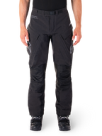 Alpinestars Hyde XT Drystar Hose, schwarze Adventure-Touring-Hose, getragen von einem Fahrer mit schwarzen Stiefeln, graue Logos auf den Oberschenkeln, integrierter Gürtel, verstärkte Kniepaneele, wasserdichte Textilkonstruktion.