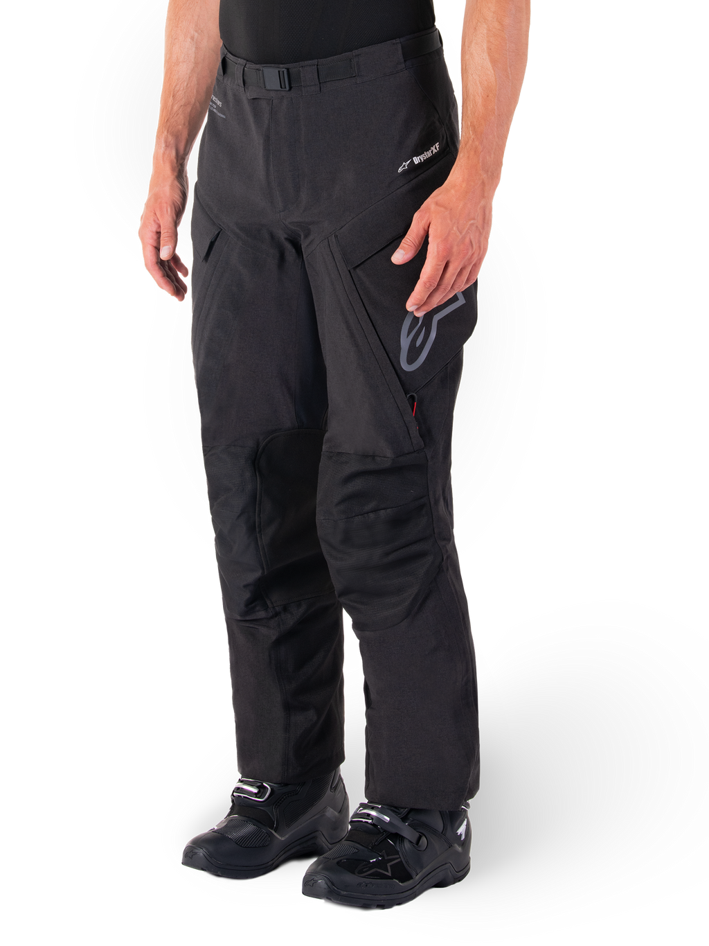 Alpinestars Hyde XT Drystar® Hose, Adventure Touring Motorradhose, Schwarz, getragen mit schwarzen Stiefeln, mit Branding der laminierten Drystar®XF-Membran, verstärkten Knieeinsätzen und Cargo-Taschen mit Reißverschluss.