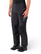 Alpinestars Hyde XT Drystar® Hose, Adventure Touring Motorradhose, Schwarz, getragen mit schwarzen Stiefeln, mit Branding der laminierten Drystar®XF-Membran, verstärkten Knieeinsätzen und Cargo-Taschen mit Reißverschluss.