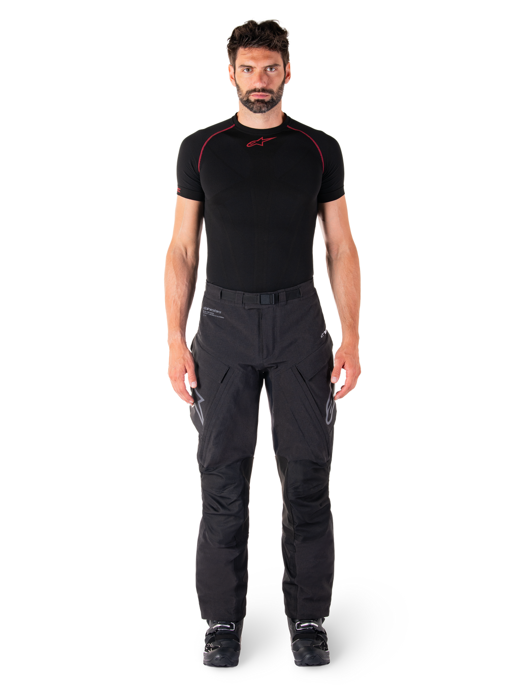 Alpinestars Hyde XT Drystar® Hose, Adventure-Touring-Motorradhose, Schwarz, getragen von einem Model mit schwarzem kurzärmeligem Base Layer und schwarzen Stiefeln, mit technischem Stretchmaterial, verstärkten Knieeinsätzen und ergonomischen Cargo-Taschen.