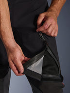 Alpinestars Halo Pro Drystar® XF Laminated Pants, Black, close-up of a person opening the thigh vent with a waterproof zipper, revealing a black mesh lining for direct ventilation, functional adventure motorcycle pants detail.
