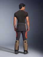 Alpinestars Halo Pro Drystar® XF Gelamineerde Broek, Walnut Rust Black adventure motorbroek, achteraanzicht op een model met zwarte laarzen en een basislaag met korte mouwen, voorzien van walnootkleurige onderbenen, roestoranje accenten en zwarte versterkte panelen.