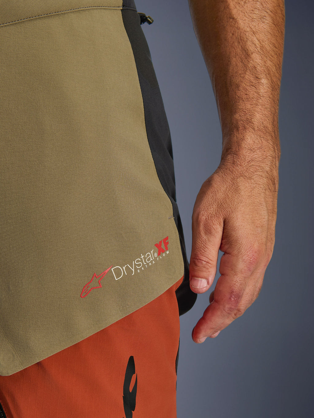 Alpinestars Halo Pro Drystar® XF Gelamineerde Broek, Walnut Rust Black, close-up detail van de Drystar XF Extra Flow-branding, met olijfgroene en roestoranje textielpanelen en technische constructie.