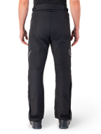 Alpinestars St-1 Waterproof Pants, Motorcycle Touring Pants, Black, back view showing reflective detailing on thighs and adjustable ankle closures, worn with black boots, minimalist design for all-weather road and adventure riding