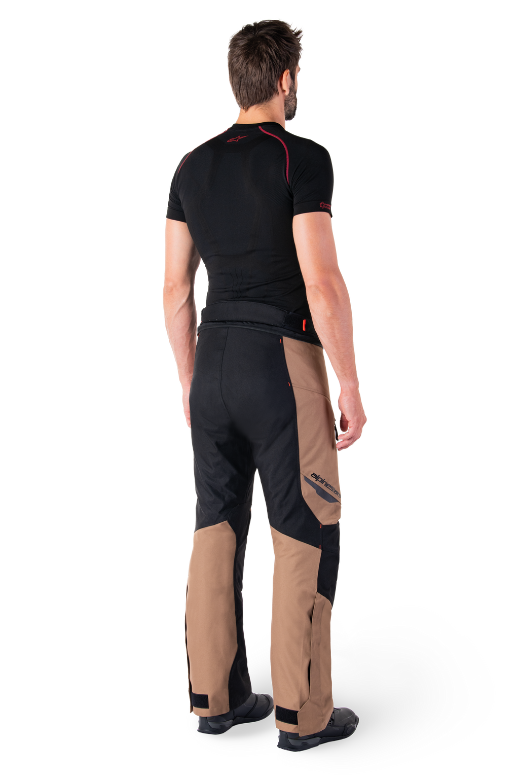 Alpinestars St-1 Waterproof Pants, motorcycle touring pants, Dark Khaki Sand and Black with Red Fluo accents, rear view on a model, featuring durable textile panels, Alpinestars logo on the thigh, and adjustable ankle cuffs, designed for all-weather adventure riding.