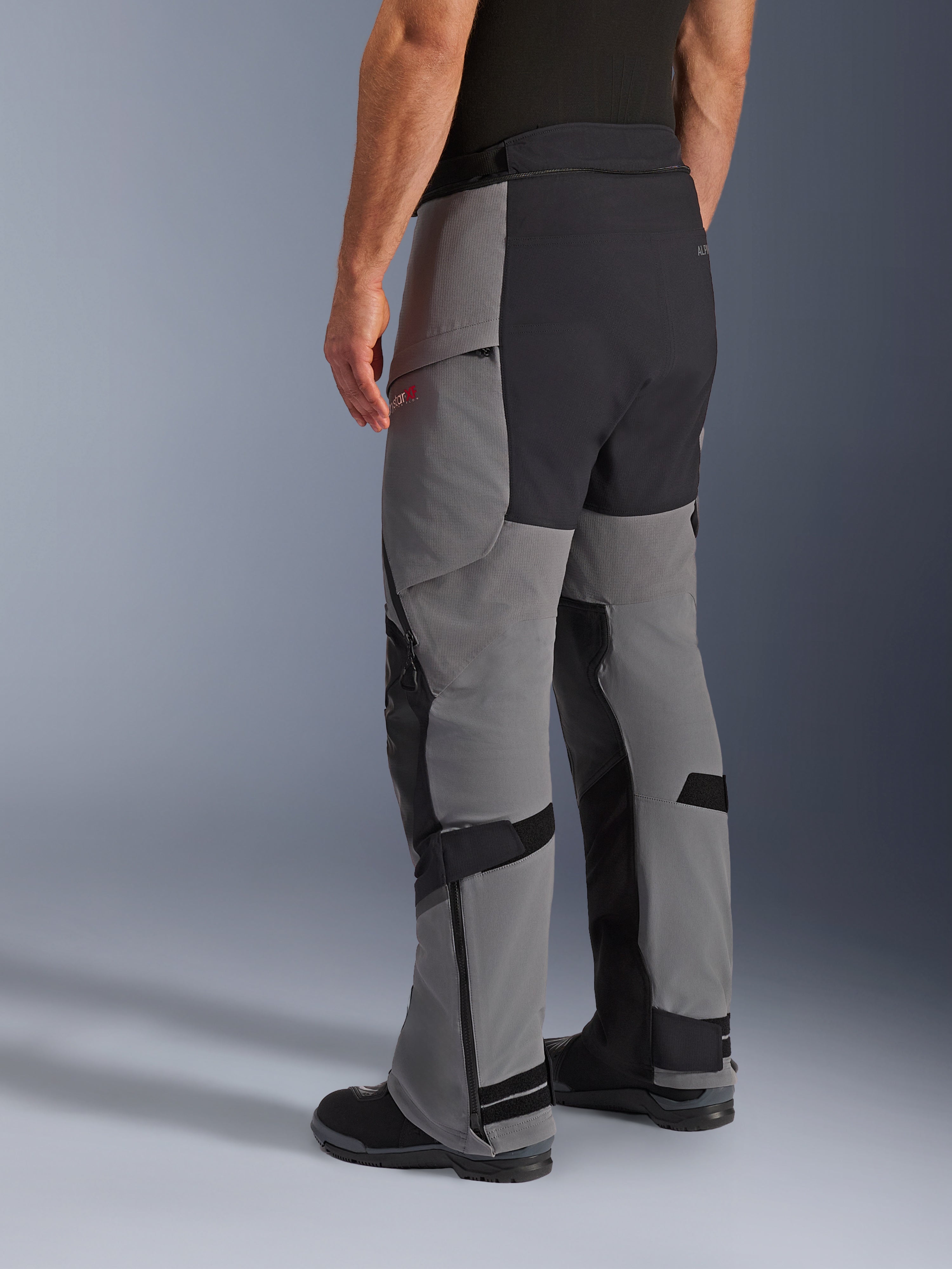 Alpinestars Andes Pro Drystar® XF Hose, Adventure-Motorradhose, Dunkelgrau und Schwarz, Dreiviertelansicht von hinten, Textilkonstruktion mit schwarzem verstärktem Gesäß und Innenbein-Einsätzen, Reißverschlüssen an den Unterschenkeln und verstellbaren Laschen.