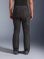 Alpinestars Cusco Drystar® Pants, Motorcycle Pants, Black, rear view worn by a rider, featuring textured textile panels, zippered vents on the thighs, and adjustable ankle closures, paired with black Alpinestars boots.