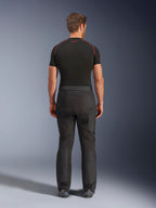 Rider wearing Alpinestars Cusco Drystar® Pants, Black adventure motorcycle pants, back view, paired with a black short-sleeve compression shirt and black riding boots, featuring a durable textile design with articulated panels for touring
