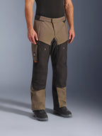 Pantalon Alpinestars Cusco Drystar®, pantalon de moto adventure, Walnut Black, présenté sur un mannequin avec des bottes noires, doté d'un design multi-panneaux marron et noir avec des poches zippées et des genoux renforcés pour le touring