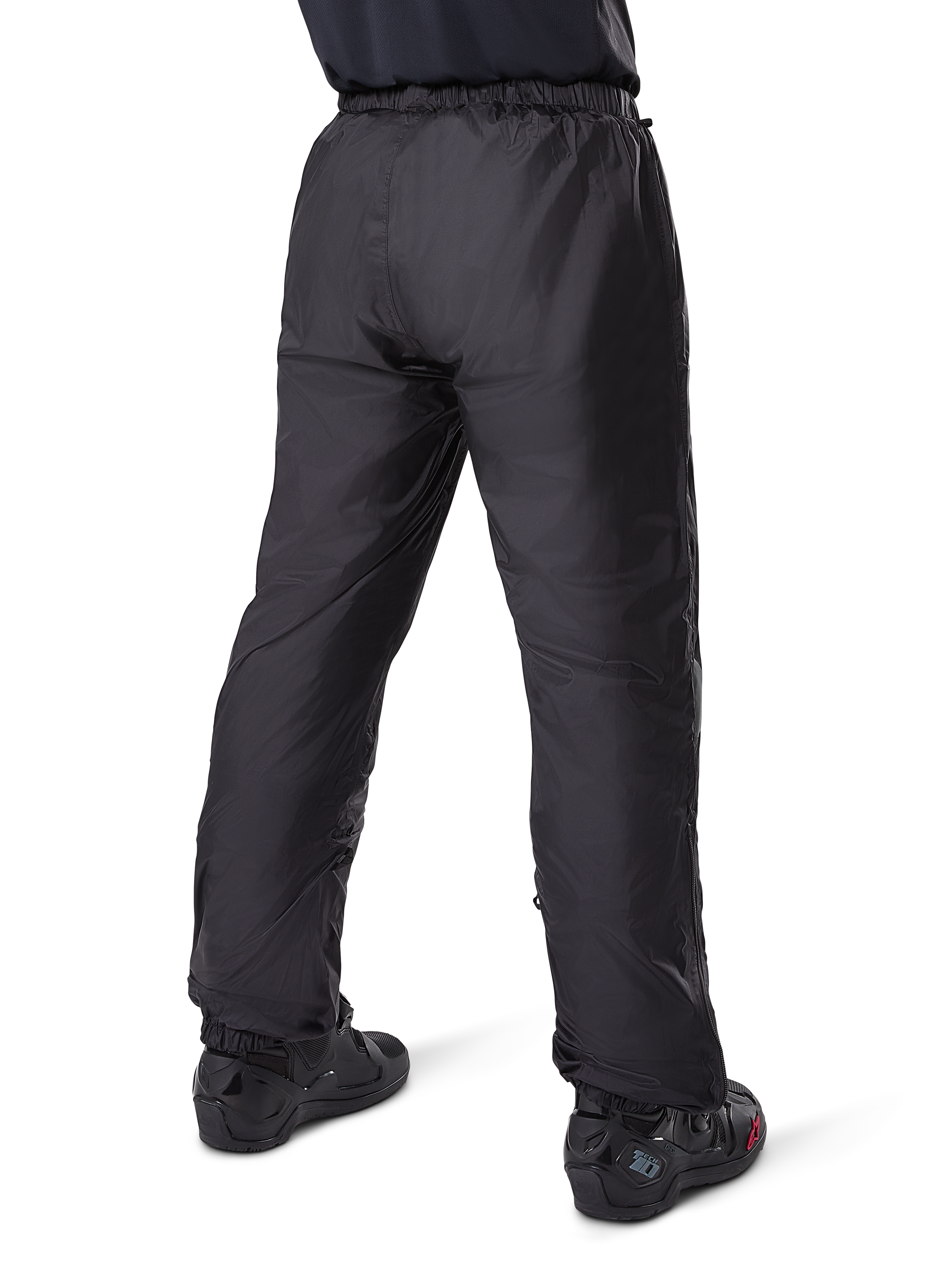 Alpinestars Bogotá Pro Drystar® 3 Seasons Pants, pantalon de moto touring aventure noir, vue arrière de la doublure imperméable Drystar® portée comme sur-pantalon, associé à des bottes de moto noires, construction technique légère pour une protection contre les intempéries multi-saisons