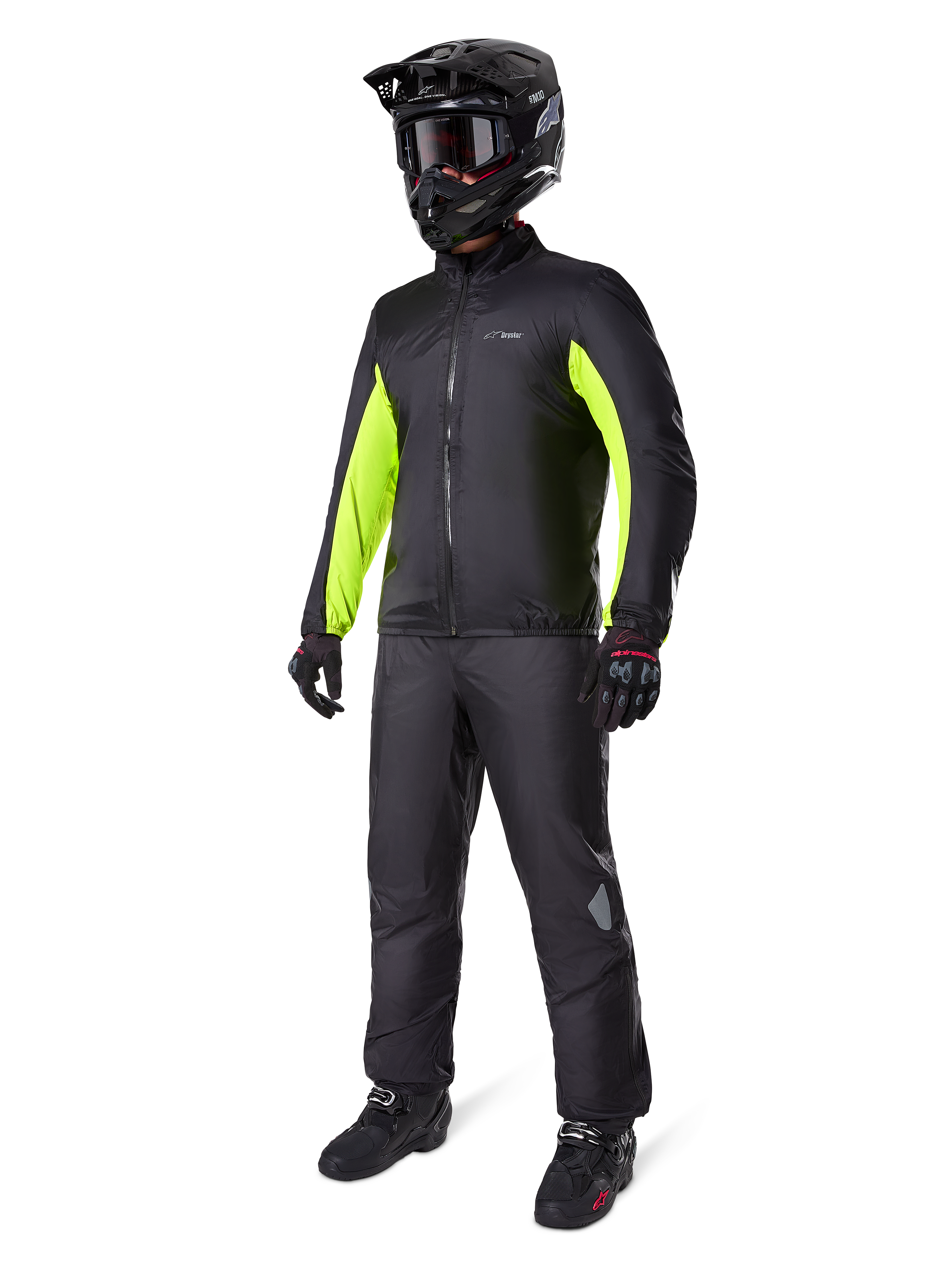 Pantalon Alpinestars Bogotá Pro Drystar® 3 Seasons, noir, motard portant un équipement complet d'aventure touring comprenant une veste noire avec des accents jaune fluo, un casque, des gants et des bottes noirs, avec la membrane imperméable Drystar® portée par-dessus le pantalon