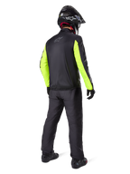 Motard vu de dos portant le pantalon Alpinestars Bogotá Pro Drystar® 3 Seasons en noir, associé à une veste noire avec des manches jaune fluorescent, un casque d'aventure noir et des bottes, équipement complet d'aventure touring