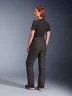 Pantalon Alpinestars Stella Andes V4 Drystar®, noir, pantalon de moto aventure présenté de trois-quarts arrière sur un mannequin, associé à un t-shirt noir et des bottes, doté de poches cargo latérales avec logo blanc et une construction en textile durable.