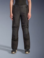 Alpinestars Stella Andes V4 Drystar, pantalon de moto d'aventure pour femme, noir, vue de face, doté de panneaux de genoux renforcés, de poches cargo résistantes à l'eau et de sangles de taille réglables, porté avec des bottes noires en studio.