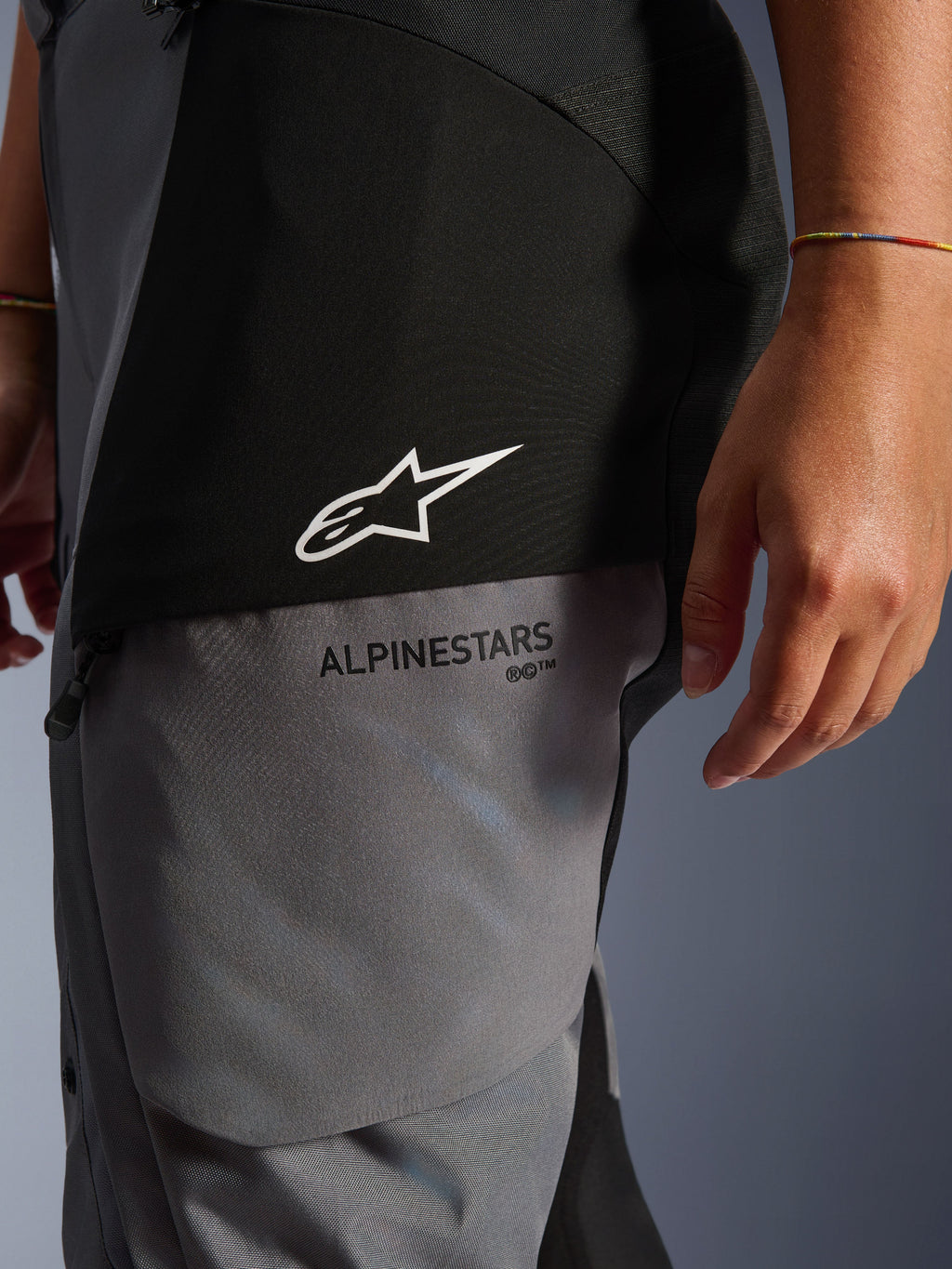 Pantalon Stella Andes V4 Drystar® pour femme, noir et gris foncé, gros plan sur le haut de la cuisse montrant le logo étoile blanc et le marquage Alpinestars noir, textile technique résistant pour le touring d'aventure
