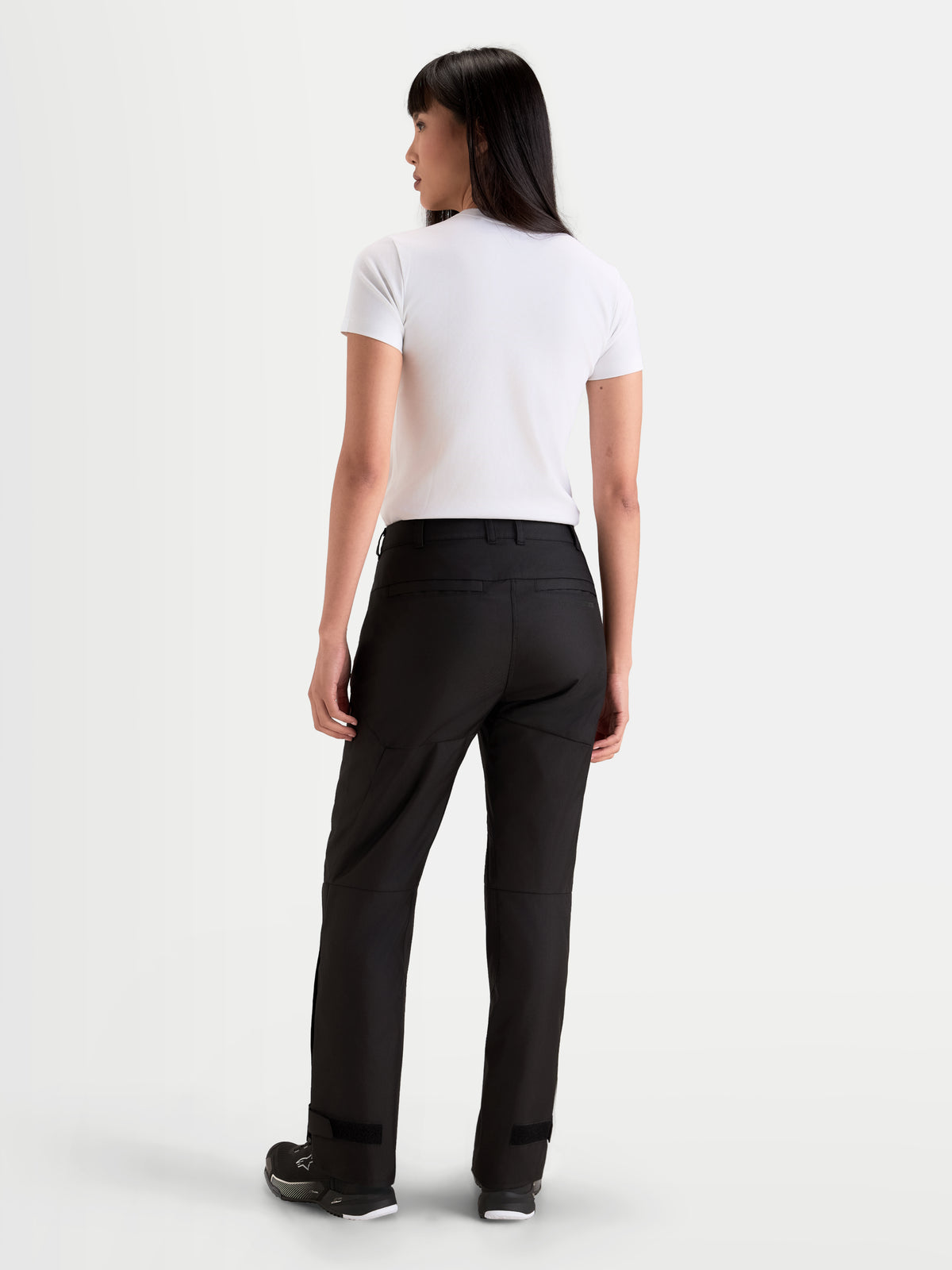 Alpinestars Stella C-1 Waterproof broek, dames motorbroek voor urban rijden in zwart, achteraanzicht op model met wit t-shirt en motorlaarzen, duurzame 450D polyfabric constructie