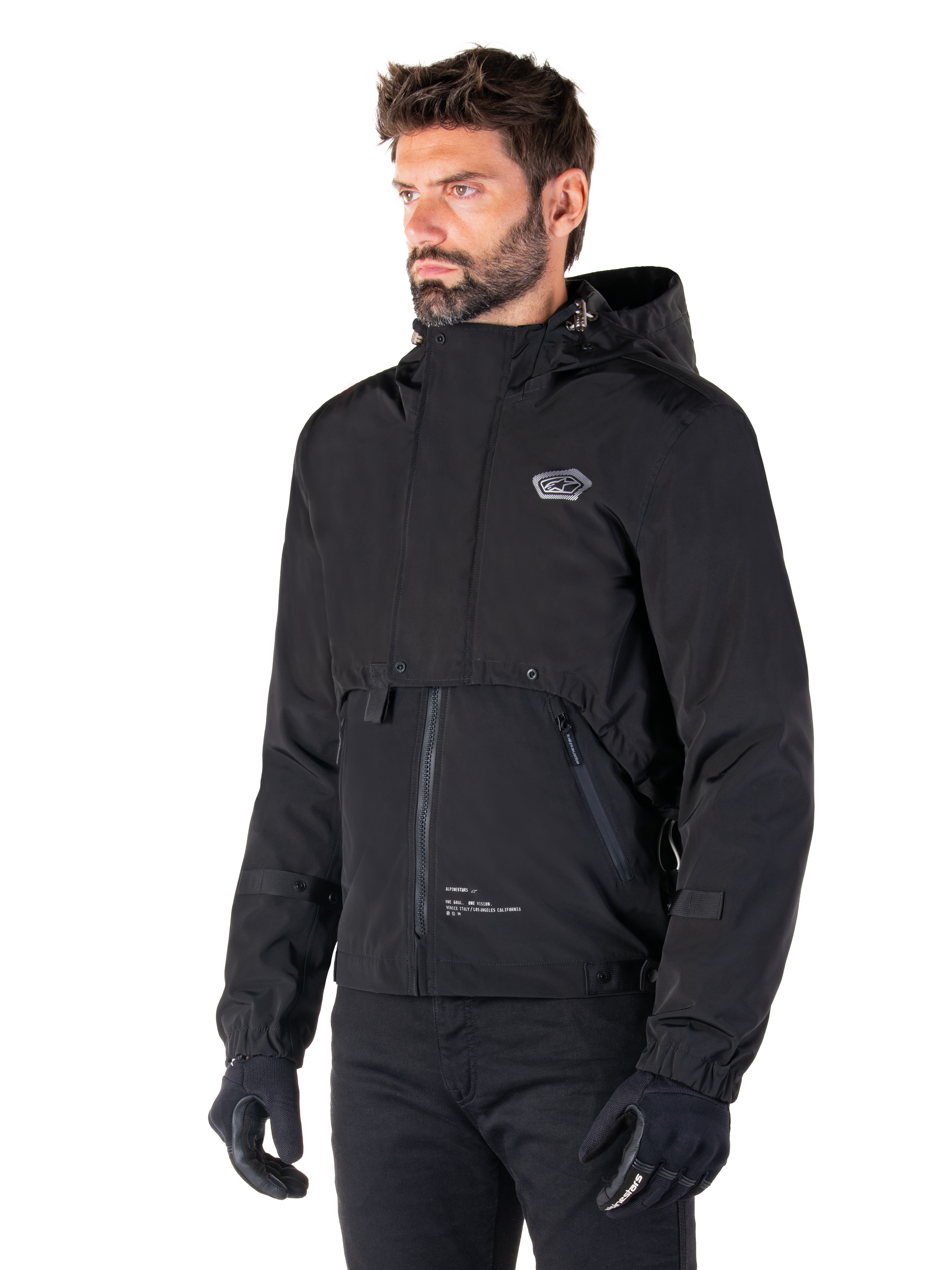 Alpinestars Mootant Waterproof Parka, Black modular motorcycle jacket, worn by a man with black gloves and pants, features a hood, front zipper, and layered utilitarian design, sleek urban aesthetic with logo on chest.
