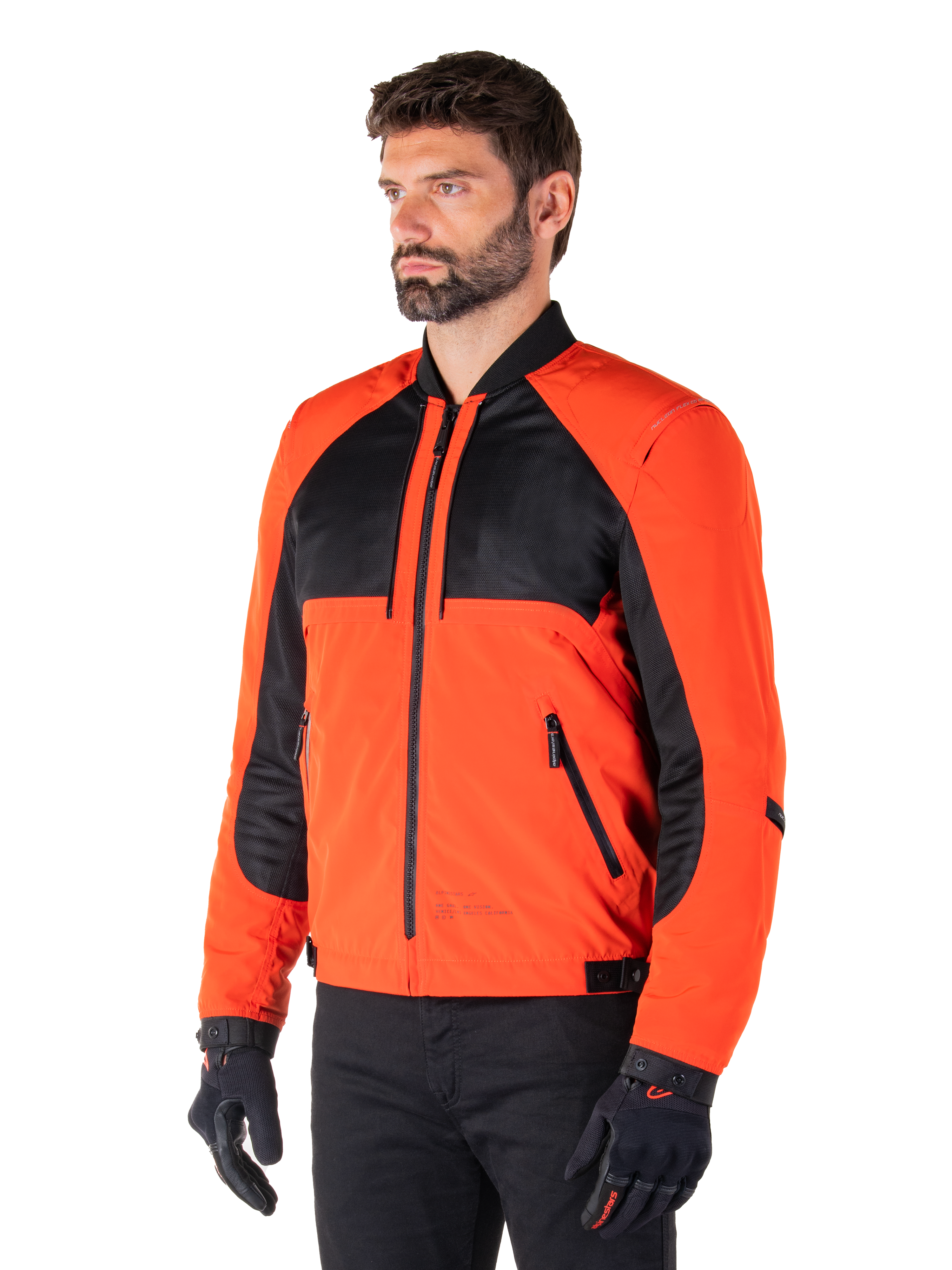 Parka imperméable Alpinestars Mootant en Orange Épicé et Noir, veste de moto modulaire présentée dans sa configuration blouson aviateur, dotée d'empiècements en maille noire et textile orange, équipement de conduite urbain contemporain porté avec des gants noirs