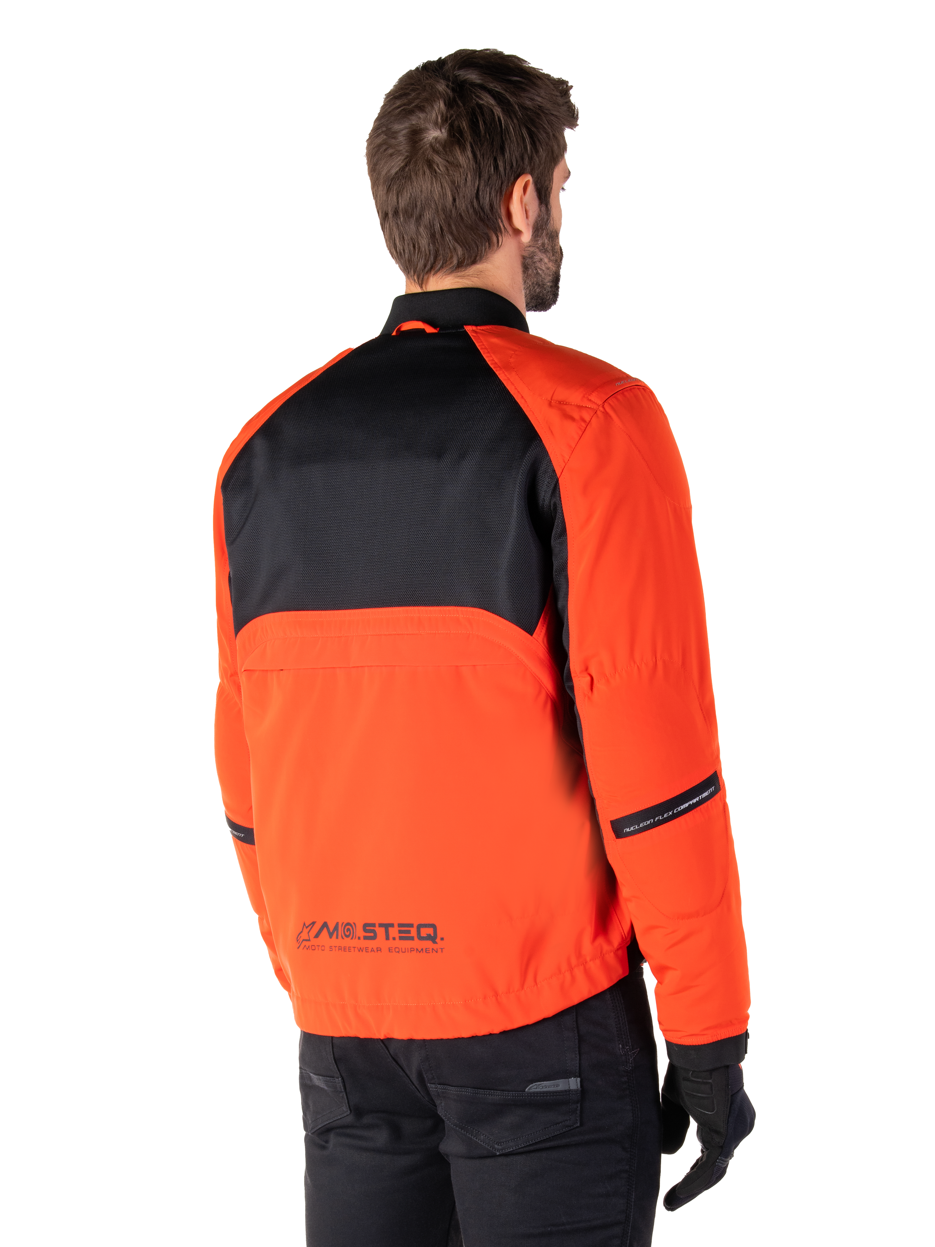 Vue arrière d'un motard portant la Parka Imperméable Alpinestars Mootant en Spicy Orange et noir, dotée d'un panneau supérieur en maille noire et du logo réfléchissant MO.ST.EQ., veste de moto utilitaire moderne.