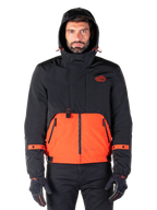 Alpinestars Mootant Waterproof Parka, veste de moto, orange épicé et noir, design modulaire toutes saisons avec capuche, poches avant zippées et détails de sangles orange sur les manches, portée par un mannequin avec des gants et un pantalon noirs