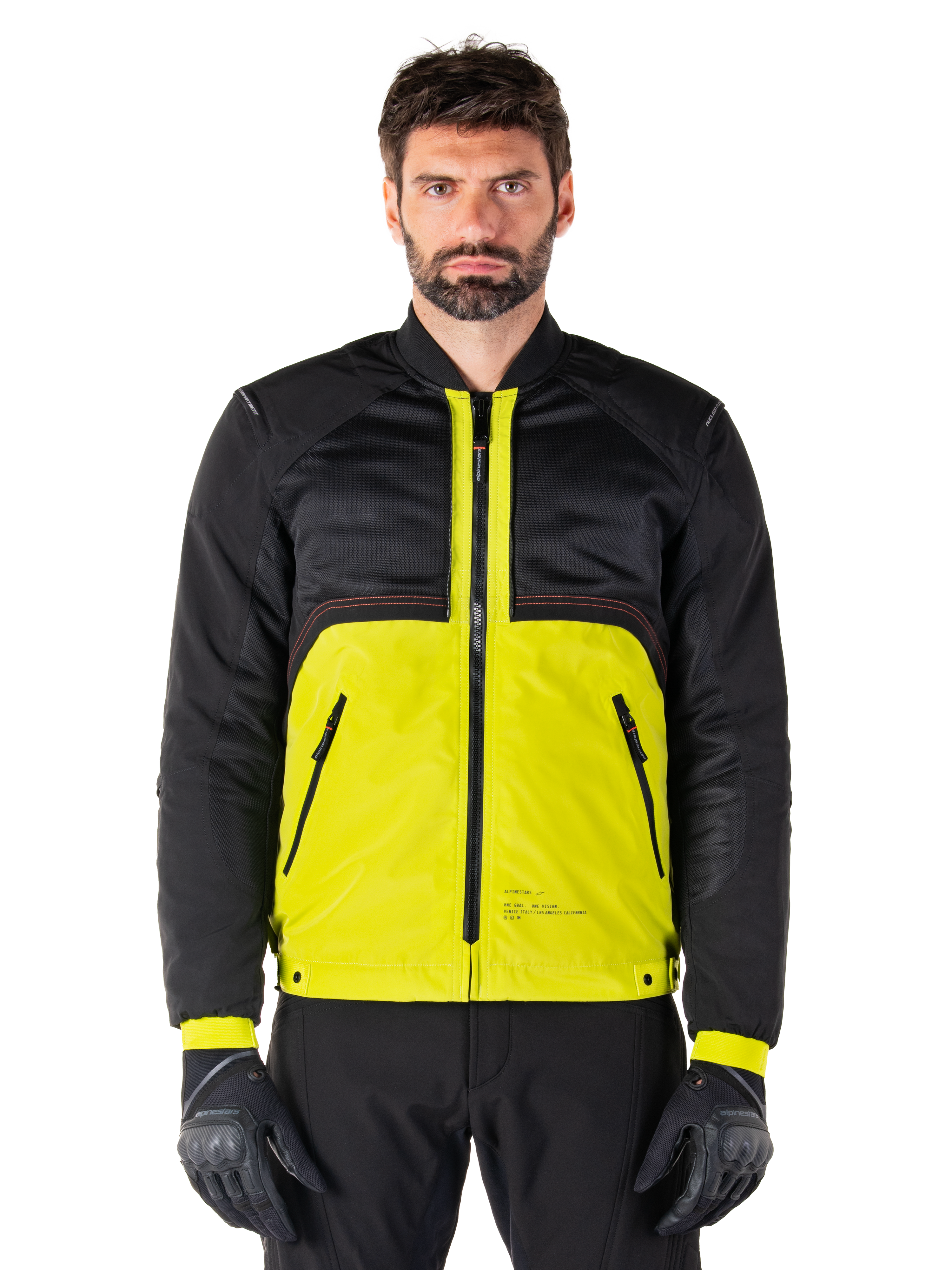 Mootant Waterproof Parka, modulaire motorjas, Lime Punch en zwart, gedragen door een mannelijk model met zwarte handschoenen en broek, met een felgeel onderlichaam en een zwart bovenstuk en mouwen, utilitair ontwerp voor rijden in alle weersomstandigheden