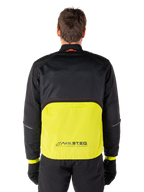 Alpinestars Mootant Waterproof Parka, motorjas, Lime Punch en zwart, achteraanzicht met zwart mesh bovenstuk voor ventilatie en limegroen onderstuk met MO.ST.EQ.-logo, gedragen met zwarte broek en handschoenen