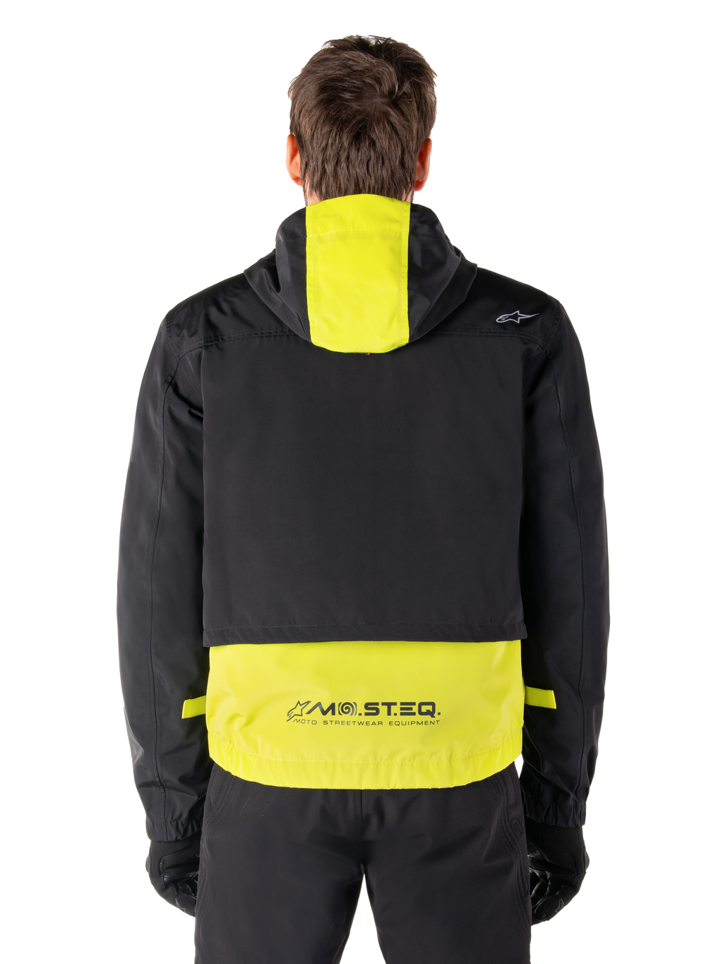 Alpinestars Mootant Waterproof Parka, motorjas, Lime Punch en zwart, achteraanzicht met capuchon en reflecterende MO.ST.EQ.-branding op de onderrug, gedragen met zwarte motorbroek en handschoenen.