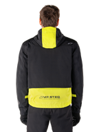 Alpinestars Mootant Waterproof Parka, motorjas, Lime Punch en zwart, achteraanzicht met capuchon en reflecterende MO.ST.EQ.-branding op de onderrug, gedragen met zwarte motorbroek en handschoenen.