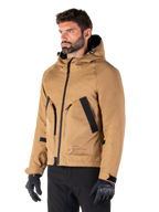 Alpinestars Morush Waterproof Parka, Utility Brown, mannelijk model draagt parka met zwarte motorhandschoenen en zwarte broek, minimalistisch op streetwear geïnspireerd ontwerp met een stormbestendige capuchon en grote voorzakken, waterdichte motorkleding