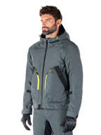 Parka imperméable Alpinestars Morush, veste de moto Urban Gray, design à capuche avec accents de fermetures éclair jaune vif, détails de poches noirs, portée avec un pantalon de moto gris assorti et des gants noirs, vêtement de moto contemporain inspiré du streetwear.